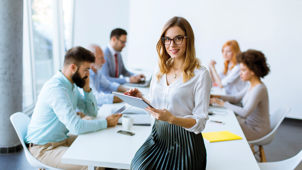 Elegant businesswoman standing in office with digital tablet stock photo