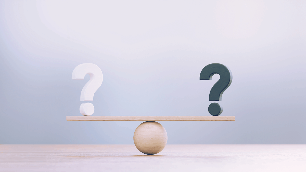 White And Black Question Marks Sitting Over Wooden Seesaw Scale Before Defocused Background