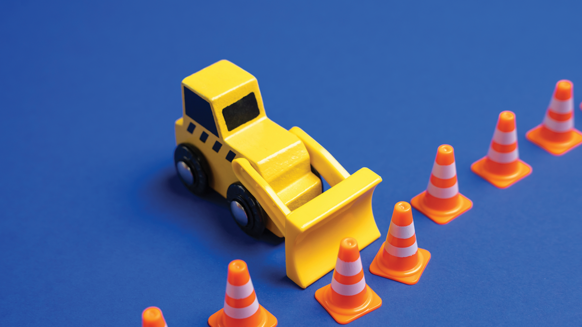 A yellow bulldozer pushes back a boundary of cones. The concept is to expand what is permitted, remove restrictions and rules. Idea of expanding freedom, lifting regulations, or redefining boundaries.